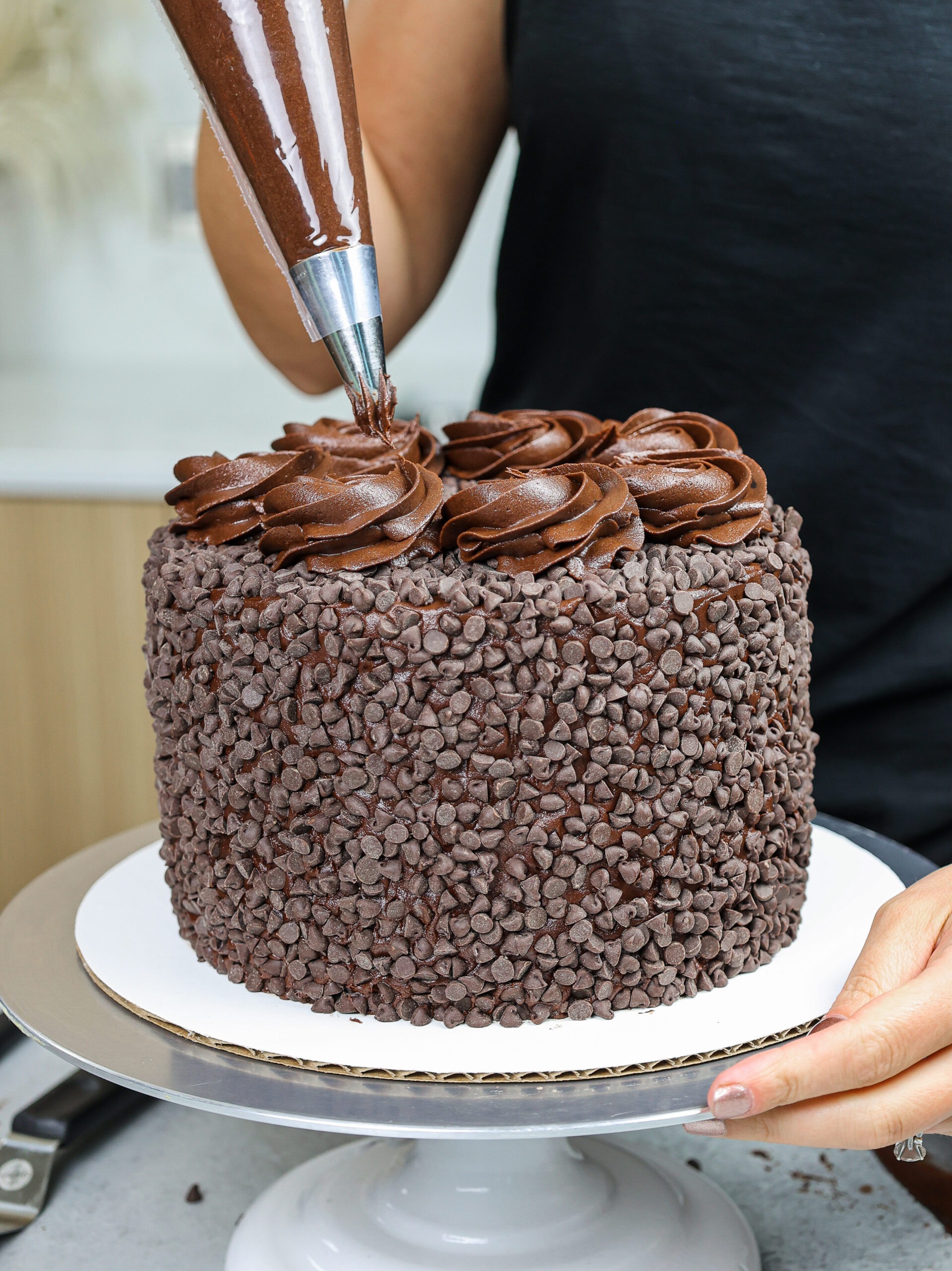 image of chocolate swirls being piped on top a death by chocolate cake