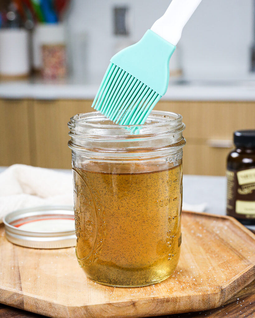 image of a silicon brush being dipped into vanilla simple syrup to soak cake layers and make them moist
