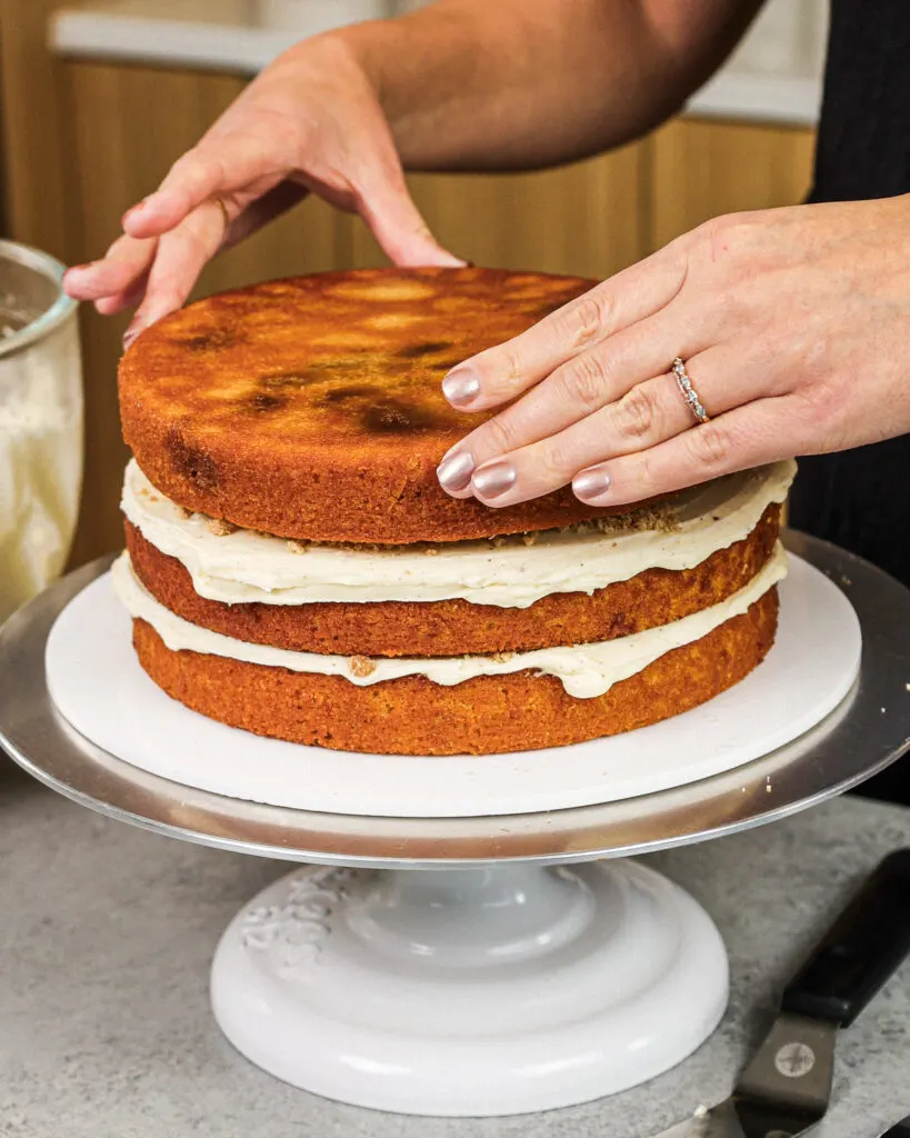 image of a cinnamon swirled cake layer being stacked to make a coffee cake layer cake