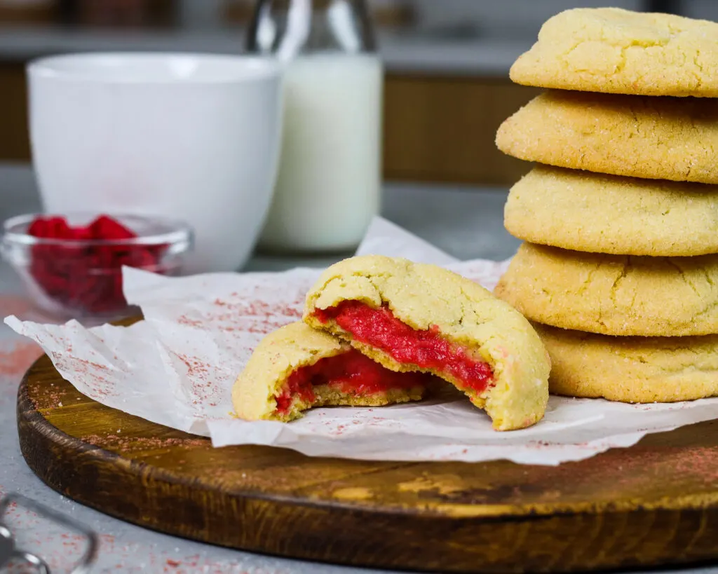 image of raspberry cheesecake cookies that have been bit into to show their raspberry cheesecake filling