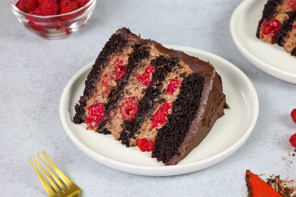 image of a slice of chocolate raspberry mousse cake made with chocolate mousse, chocolate cake layers, raspberry jam and fresh raspberries
