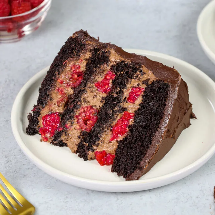 image of a slice of chocolate raspberry mousse cake made with chocolate mousse, chocolate cake layers, raspberry jam and fresh raspberries