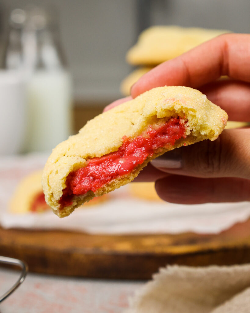 image of raspberry cheesecake cookies that have been bit into to show their raspberry cheesecake filling