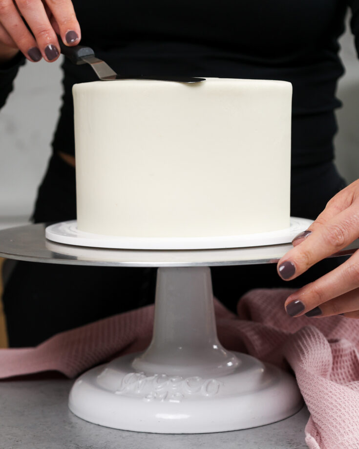 https://chelsweets.com/wp-content/uploads/2021/11/image-of-a-six-inch-cake-being-frosted-smoothly-with-buttercream-frosting-735x919.jpg