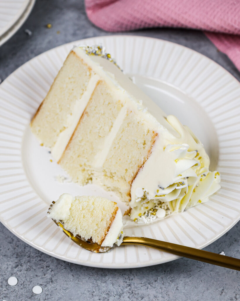 image of a slice of a small, 6-inch vanilla cake that's decorated with white drips