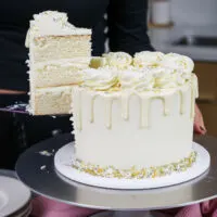 image of a slice of white drip cake that's being cut out to show it's pretty layers