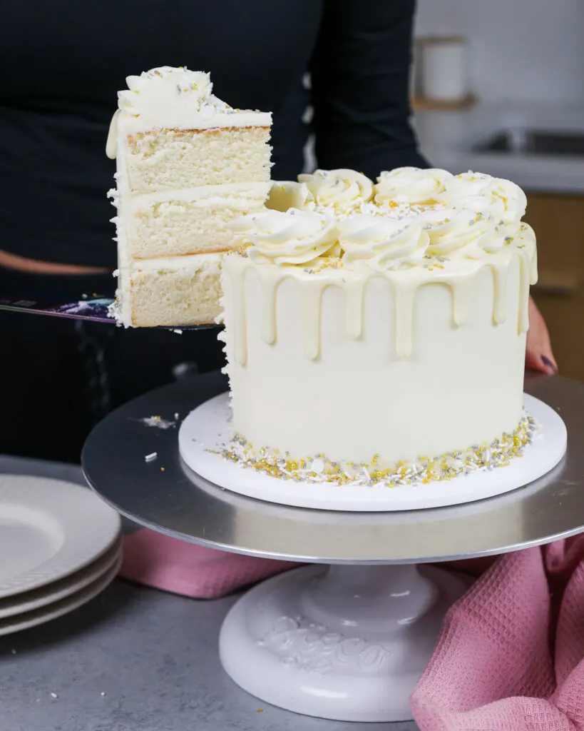 image of a slice of white drip cake that's being cut out to show it's pretty layers