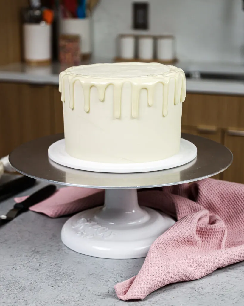image of white drips being added around a vanilla cake