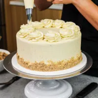 image of vanilla cake being frosted with brown butter buttercream frosting