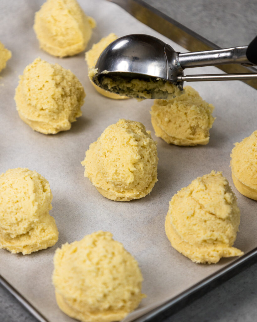 image of sugar cookie dough being scooped and then chilled to make raspberry cheesecake filled cookies