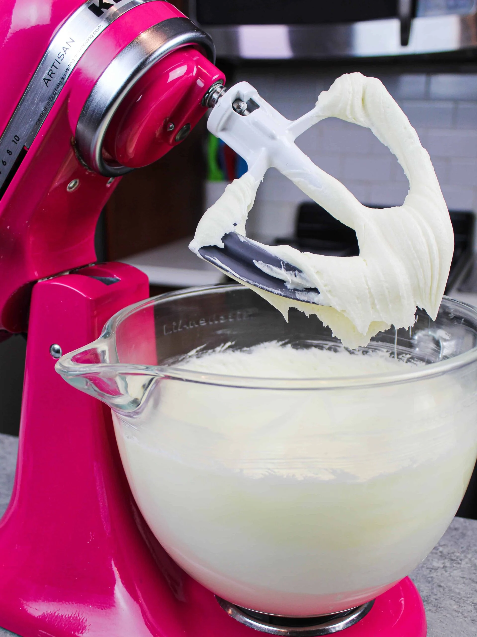 image of white chocolate buttercream frosting being made in a kitchenaid with a paddle attachment