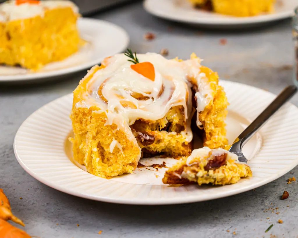 image of a fluffy carrot cake cinnamon roll that's been cut into to show how tender and soft it is