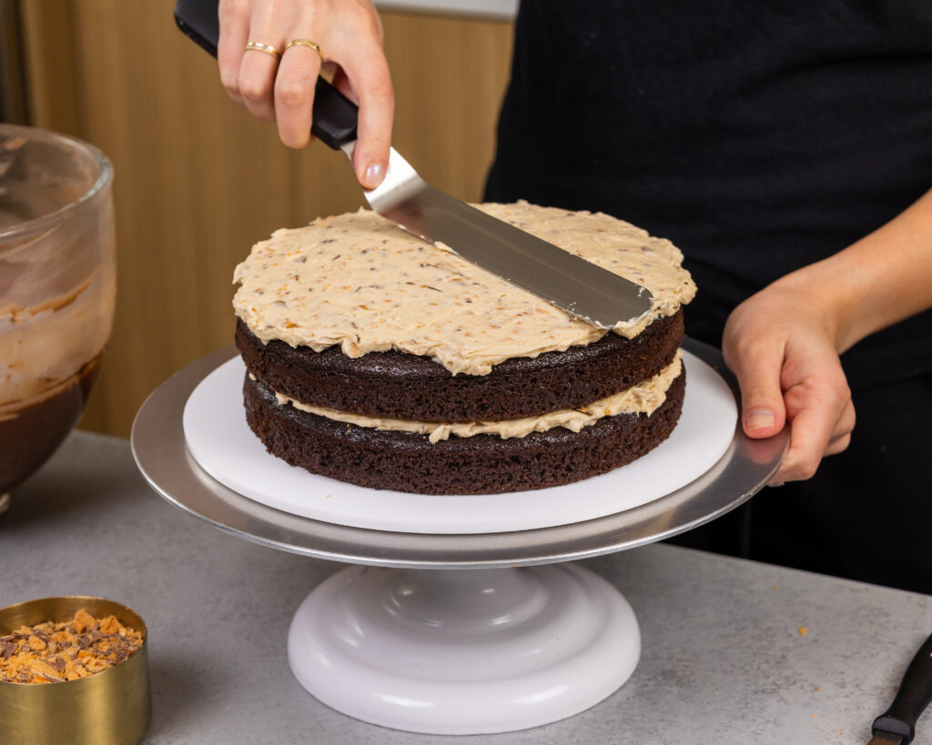 image of a butterfinger cake being filled with a crunchy peanut butter butterfinger filling