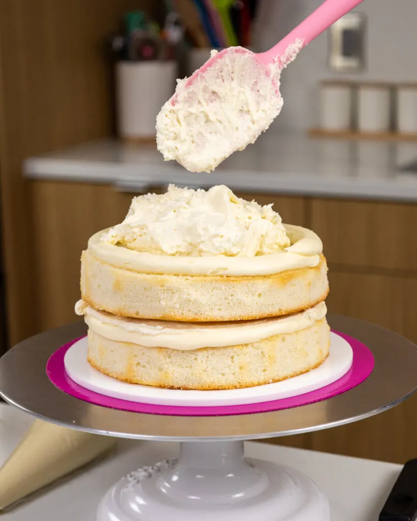 image of a white cake being filled with white chocolate mousse and white chocolate buttercream