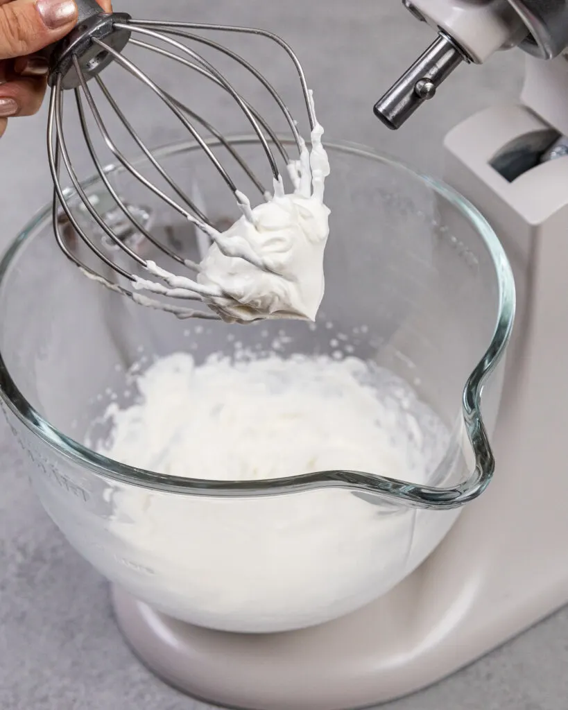 image of whipped cream that's been made using heavy whipping cream and powdered sugar with a whisk attachment and a stand mixer