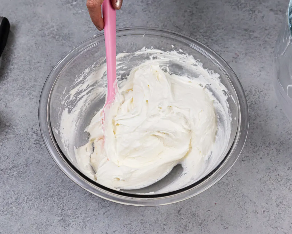 image of whipped cream being folded into the cream cheese and sugar mixture to make no bake cheesecake bites