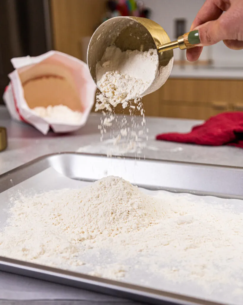 image of flour being poured onto a pan to be heat treated in the oven