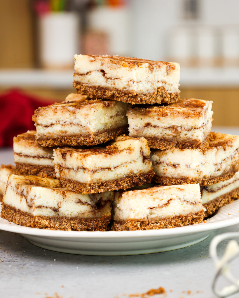 image of snickerdoodle cheesecake bars that have been cut up and stacked on a plate