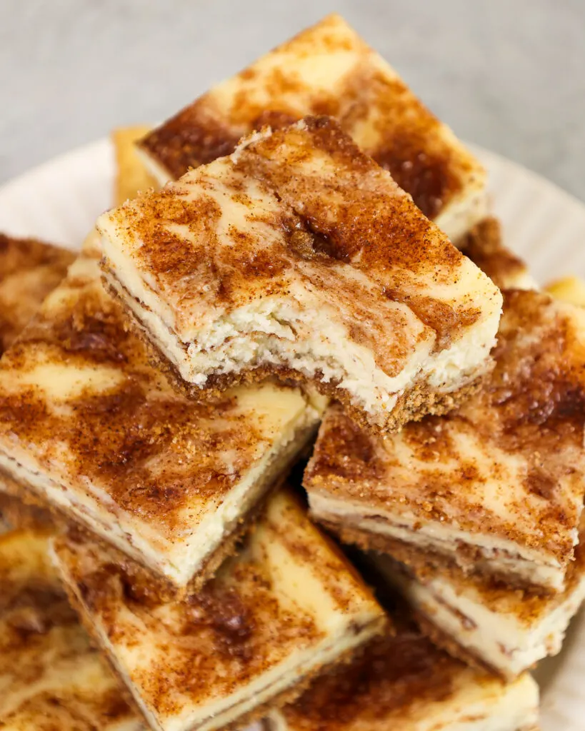 image of a snickerdoodle cheesecake bar that's been bitten into to show it's cinnamon swirl filling