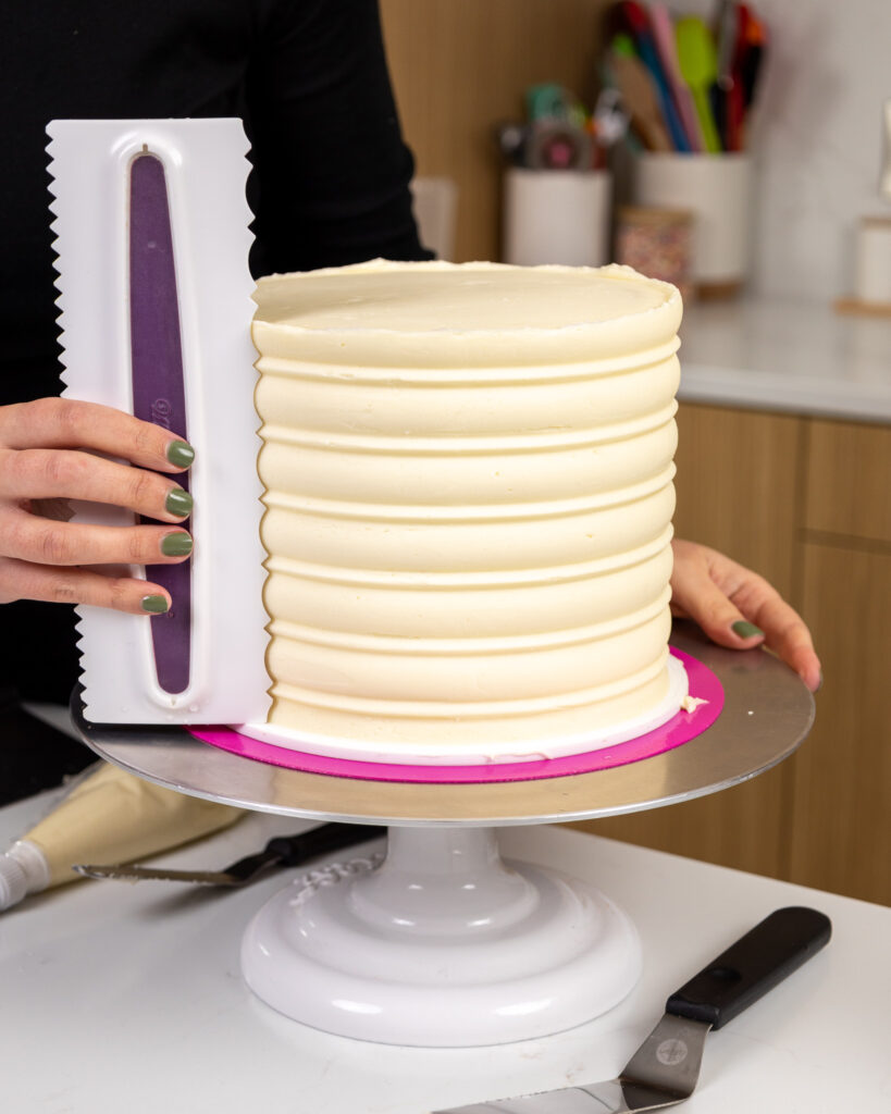 image of a white chocolate mousse layer cake being frosted with an icing comb