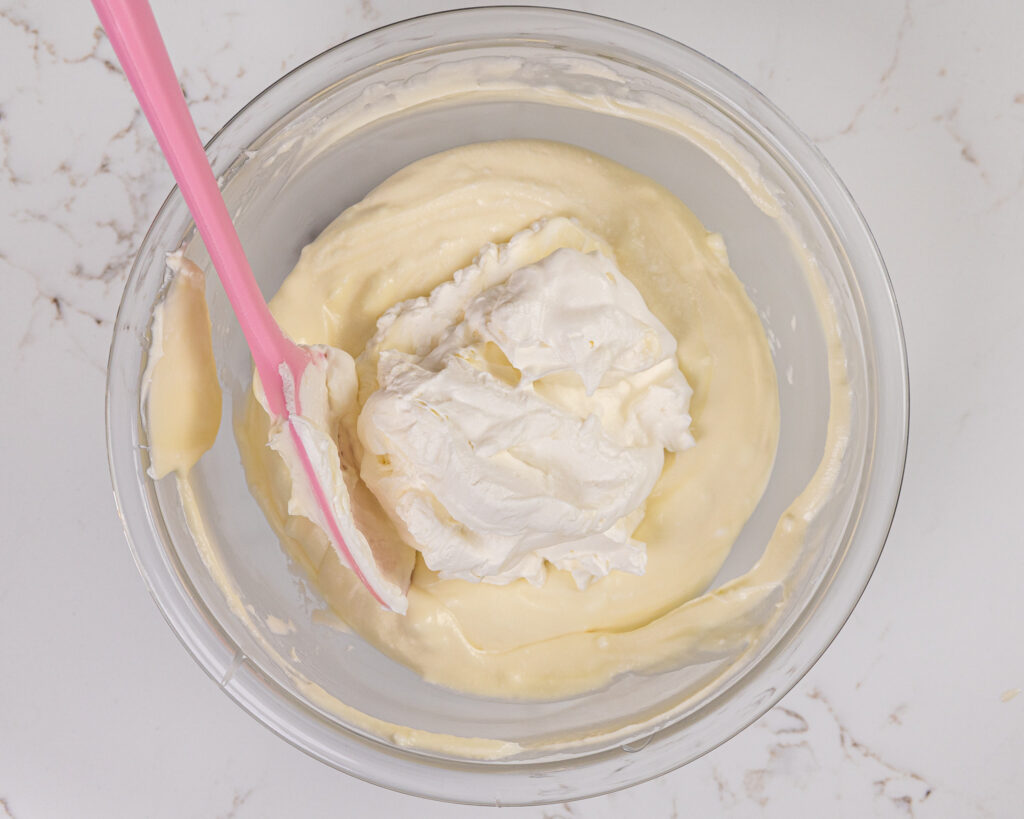 image of whipped cream being folded into white chocolate ganache to make a hazelnut mousse cake filling