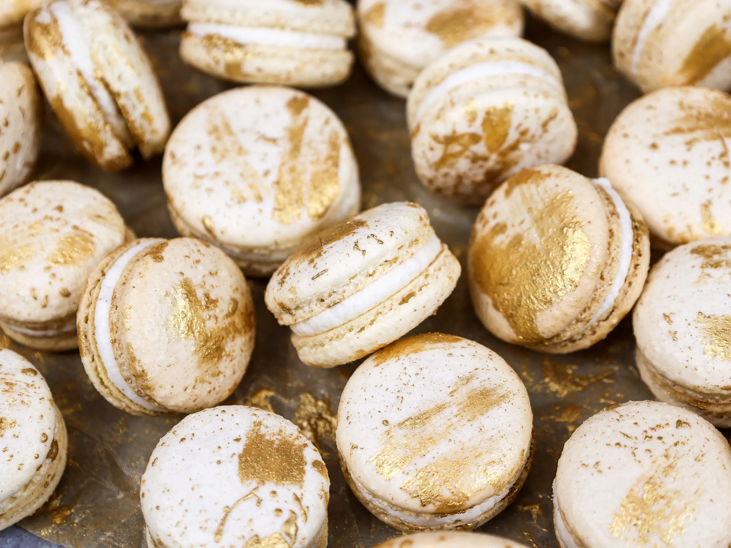 image of vanilla bean macarons made using the french method and decorated with edible gold paint