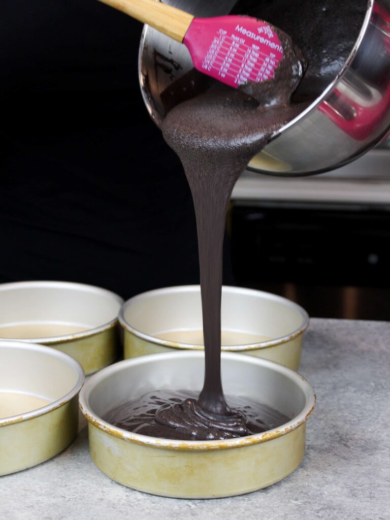 image of pouring black velvet cake batter into pans