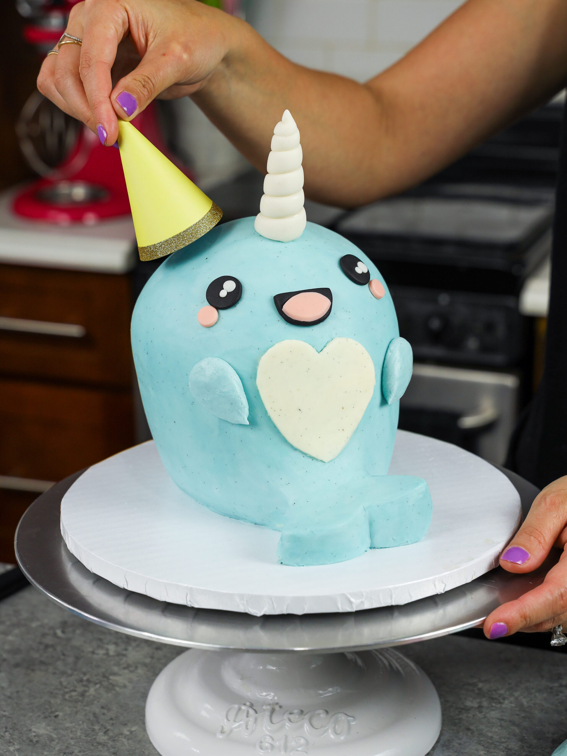 image of a party hat being added to a narwhal birthday cake