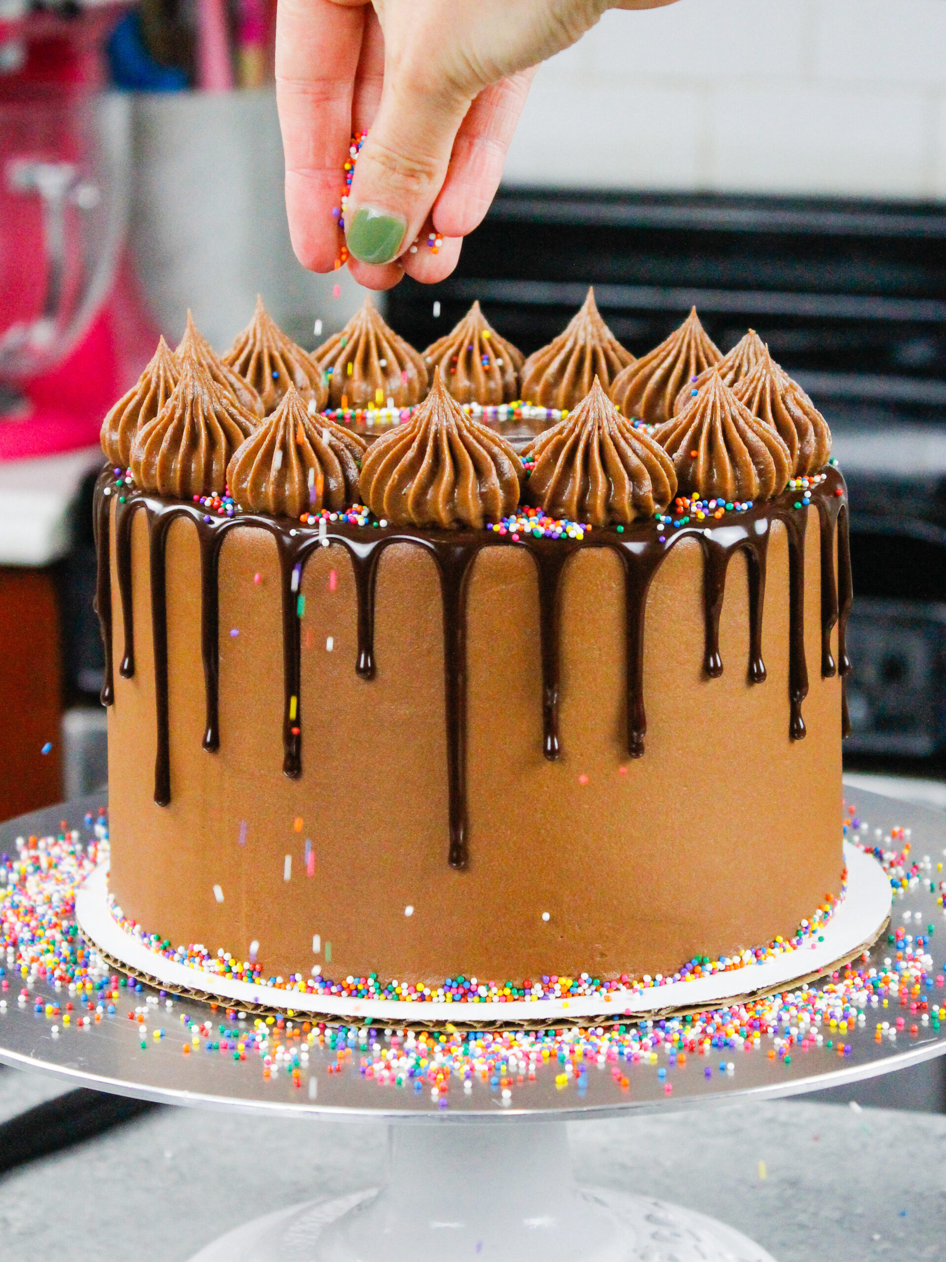 image of rainbow sprinkles being added to a chocolate drip cake