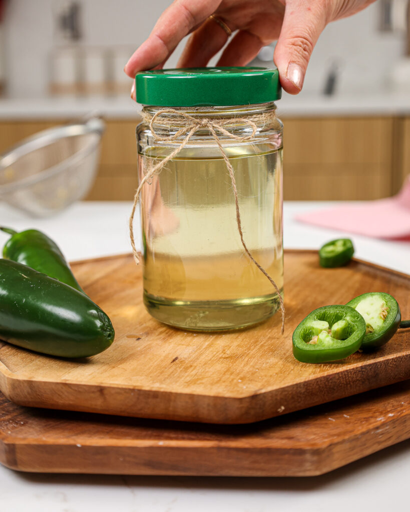 image of a lid being placed on a jar of jalapeno infused simple syrup