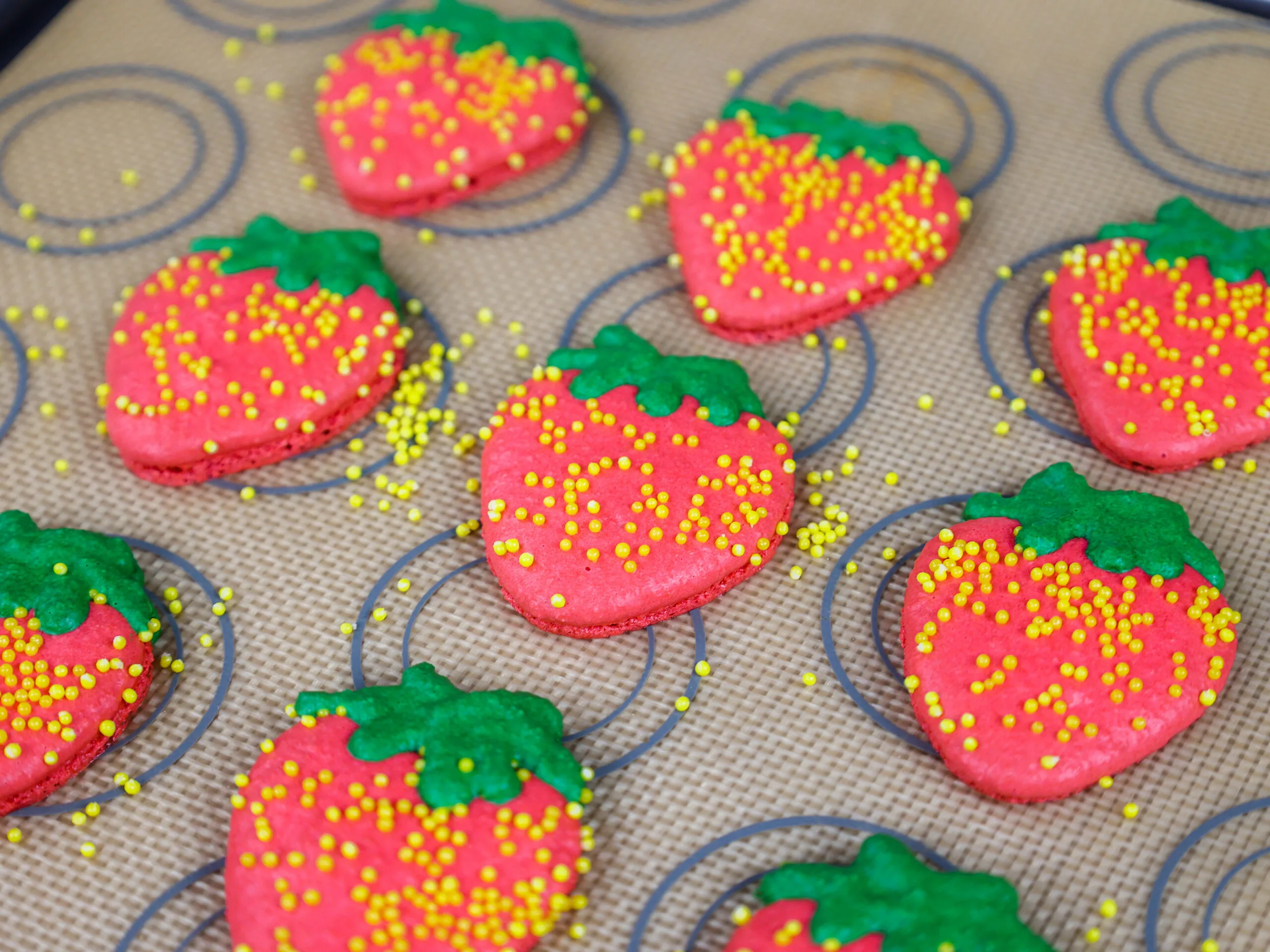 image of strawberry shaped macaron shells that have been baked and have nice feet