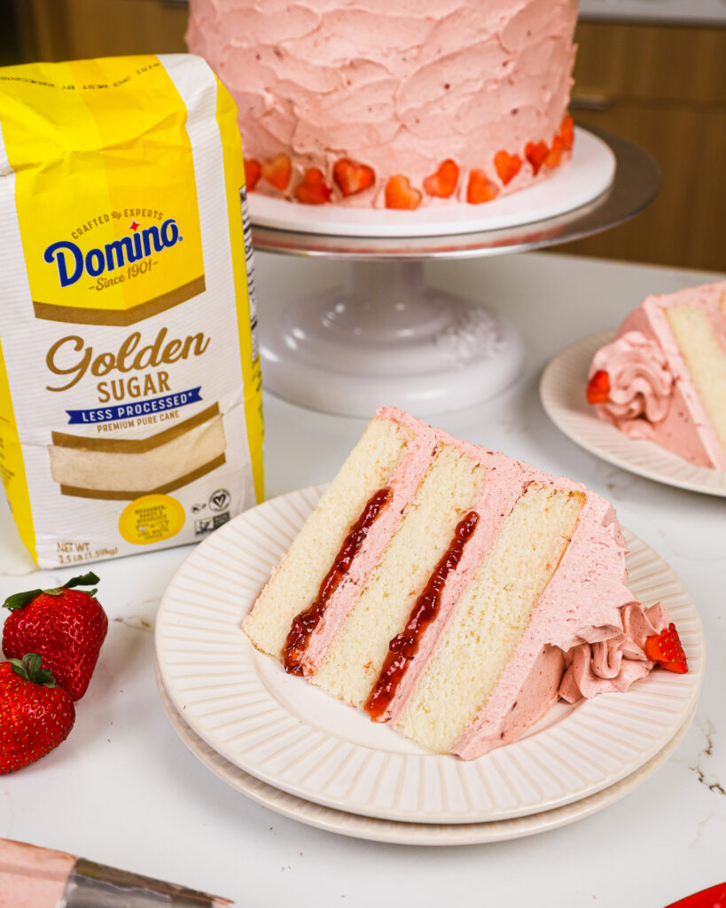 image of a golden strawberry cake made with vanilla cake layers and strawberry swiss meringue buttercream
