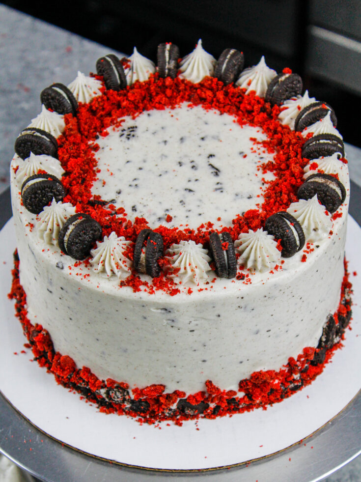 image of a red velvet oreo cake decorated with crushed oreos and red velvet cake crumbs