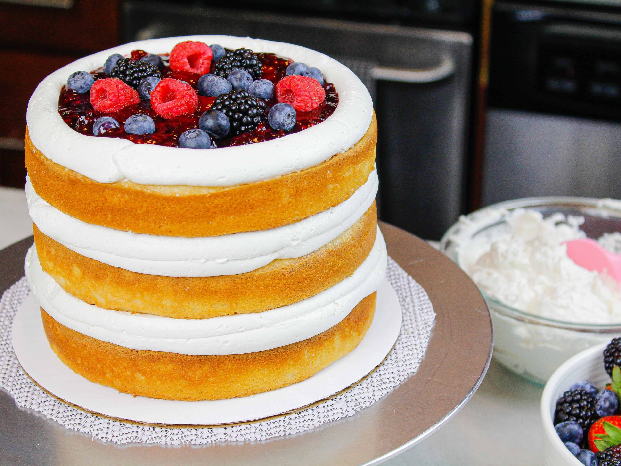 image of cake layers stacked with mixed berry filling and piped frosting dam of mascarpone cream cheese frosting