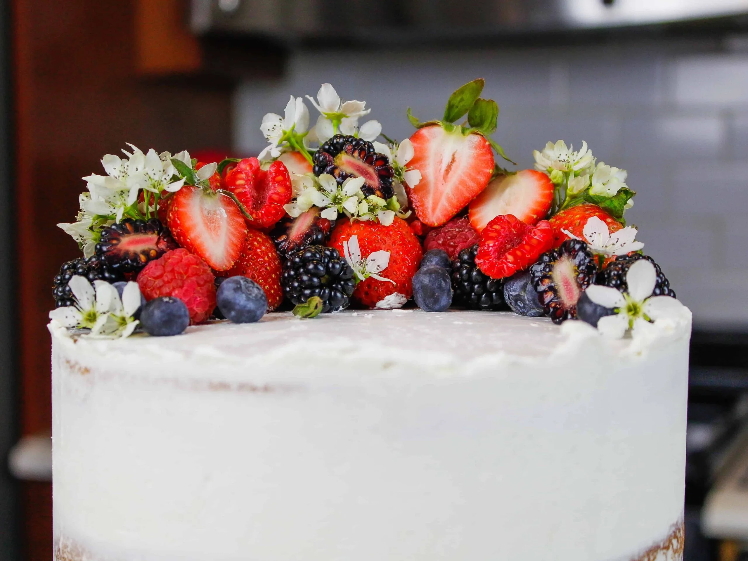 image of top of a cake decorated with fresh berries and edible flowers for spring and easter