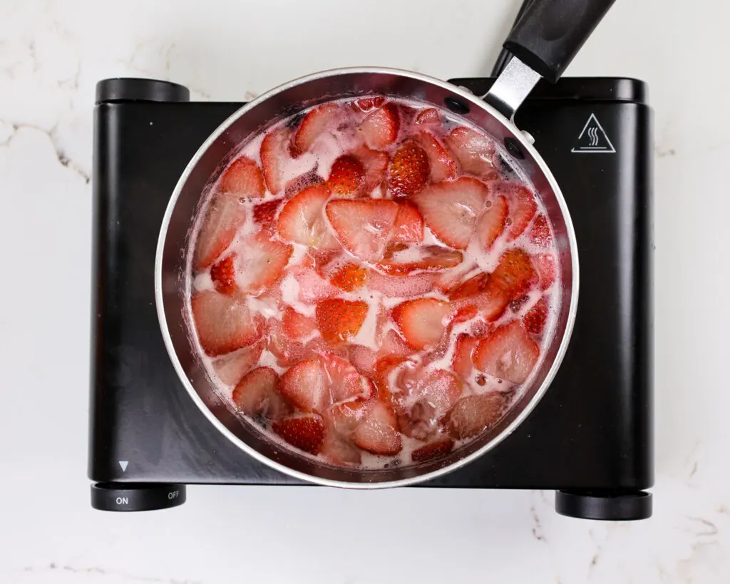 image of strawberries being heated in simple syrup to make strawberry infused simple syrup