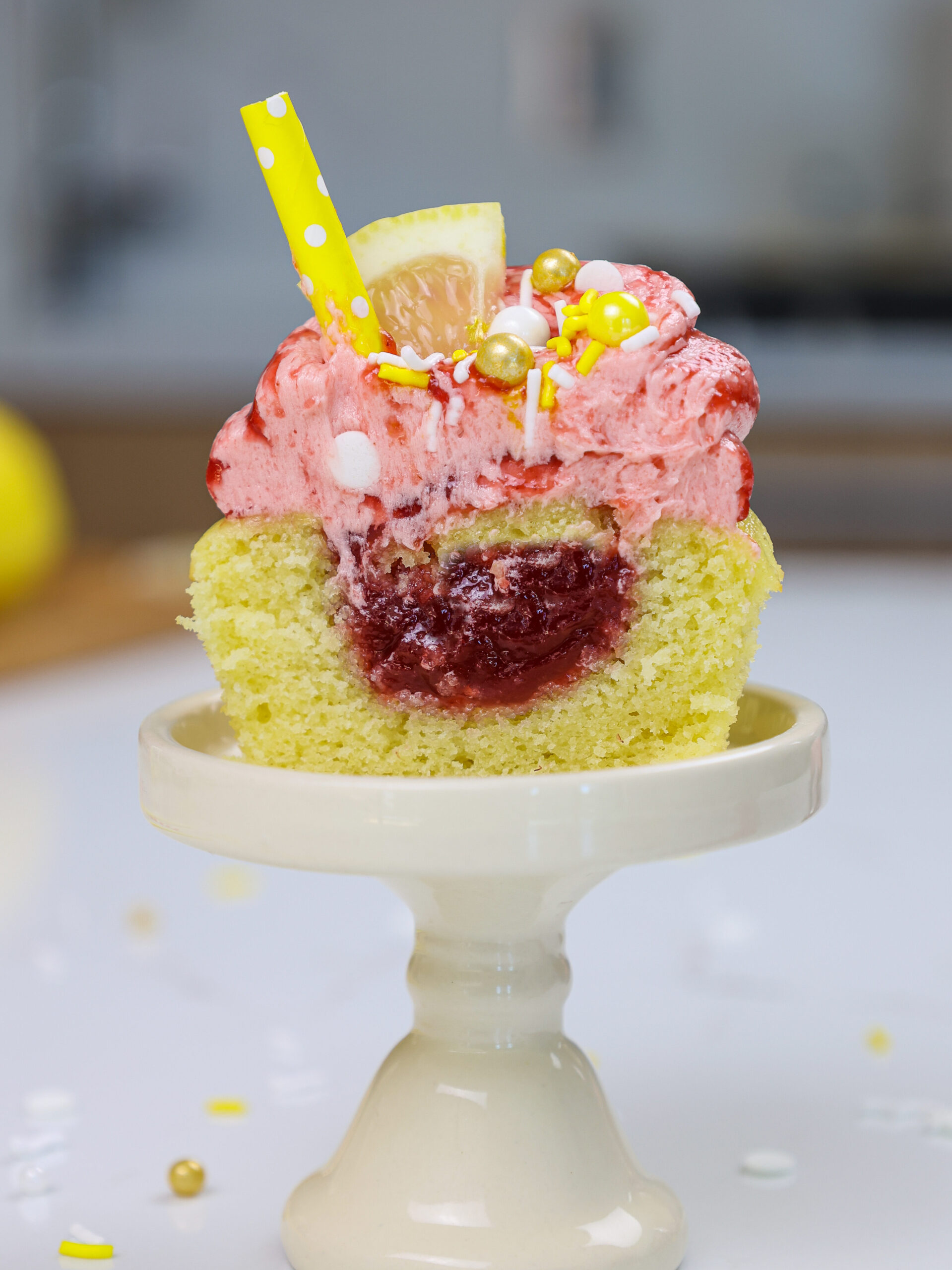 image of a raspberry lemonade cupcake that's been cut in half to show the raspberry filling inside