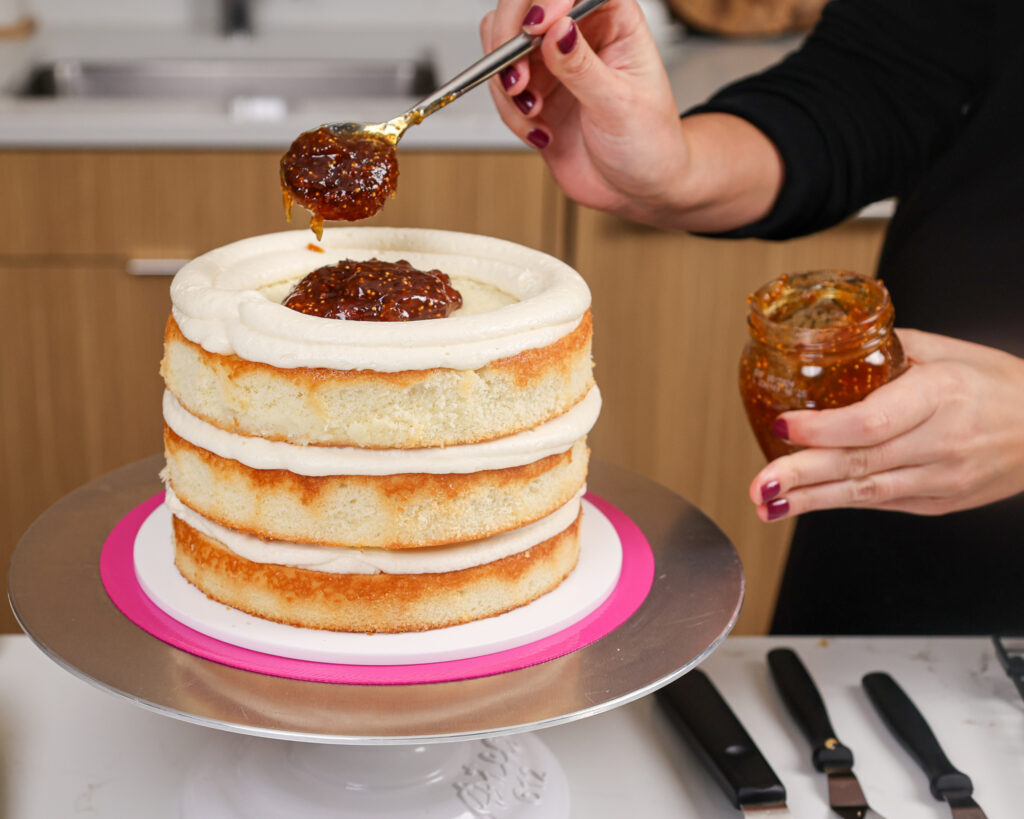 image of a cake being filled with fig jam and goat cheese frosting