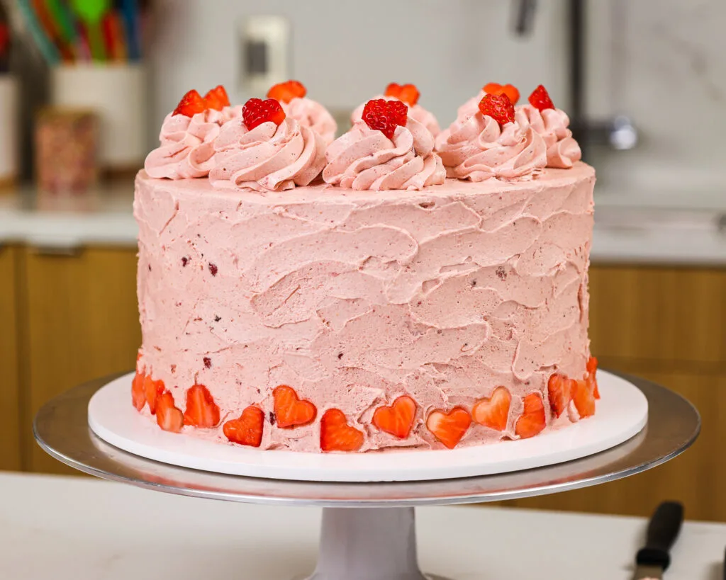 image of a golden strawberry layer cake decorated with small strawberry hearts