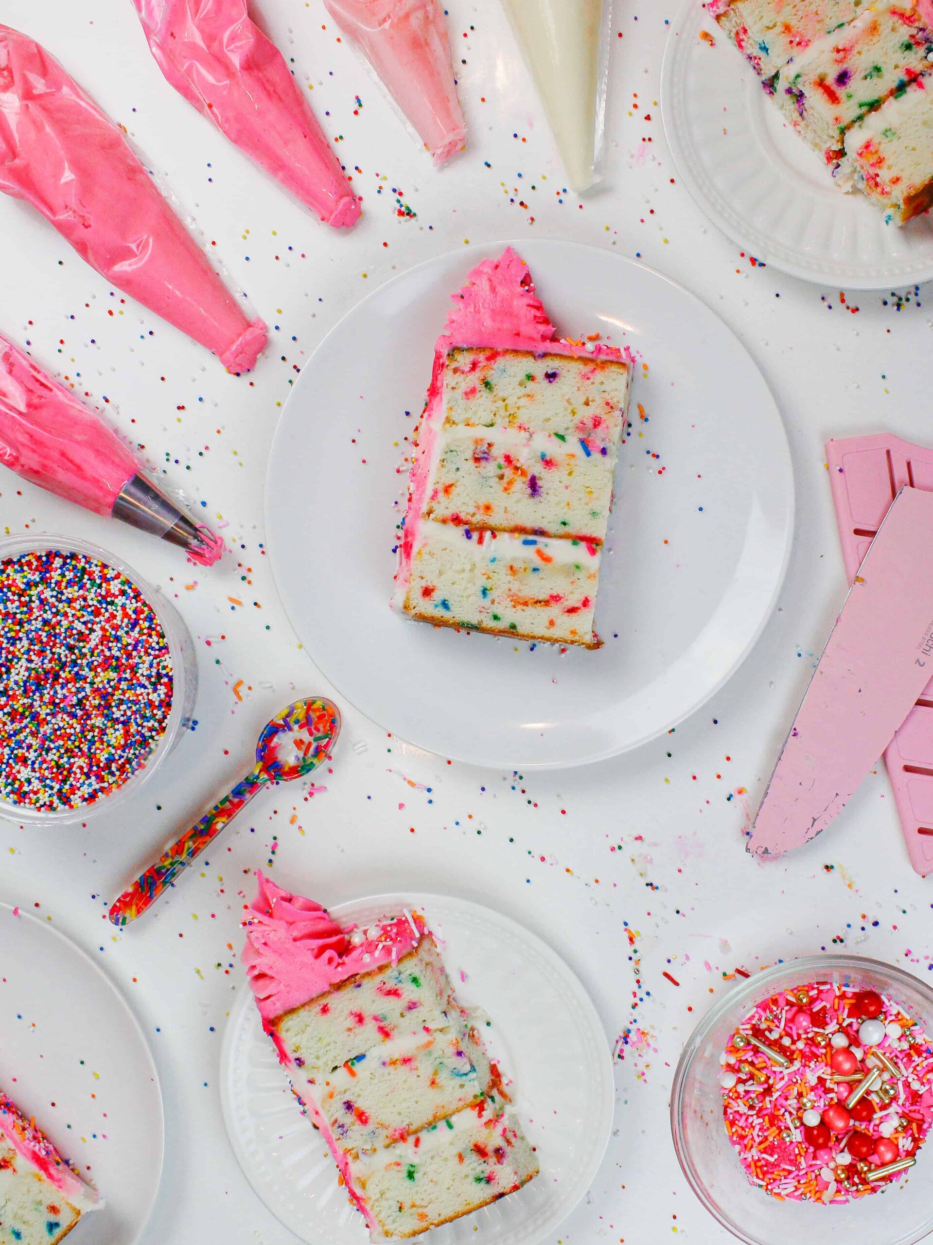 image of funfetti cake slices, cut and surrounded by pink frosting and rainbow sprinkles