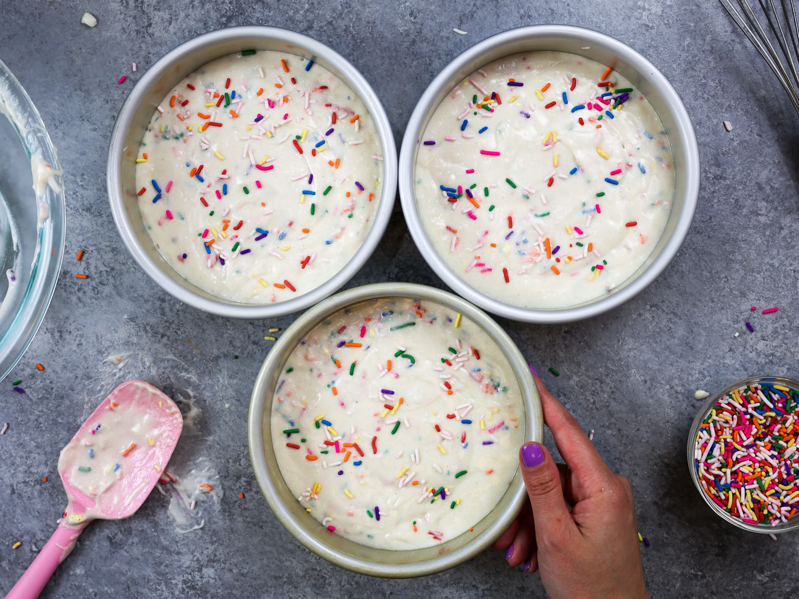 image of gluten free funfetti cake batter that's been poured in to 6-inch pans and is ready to be baked