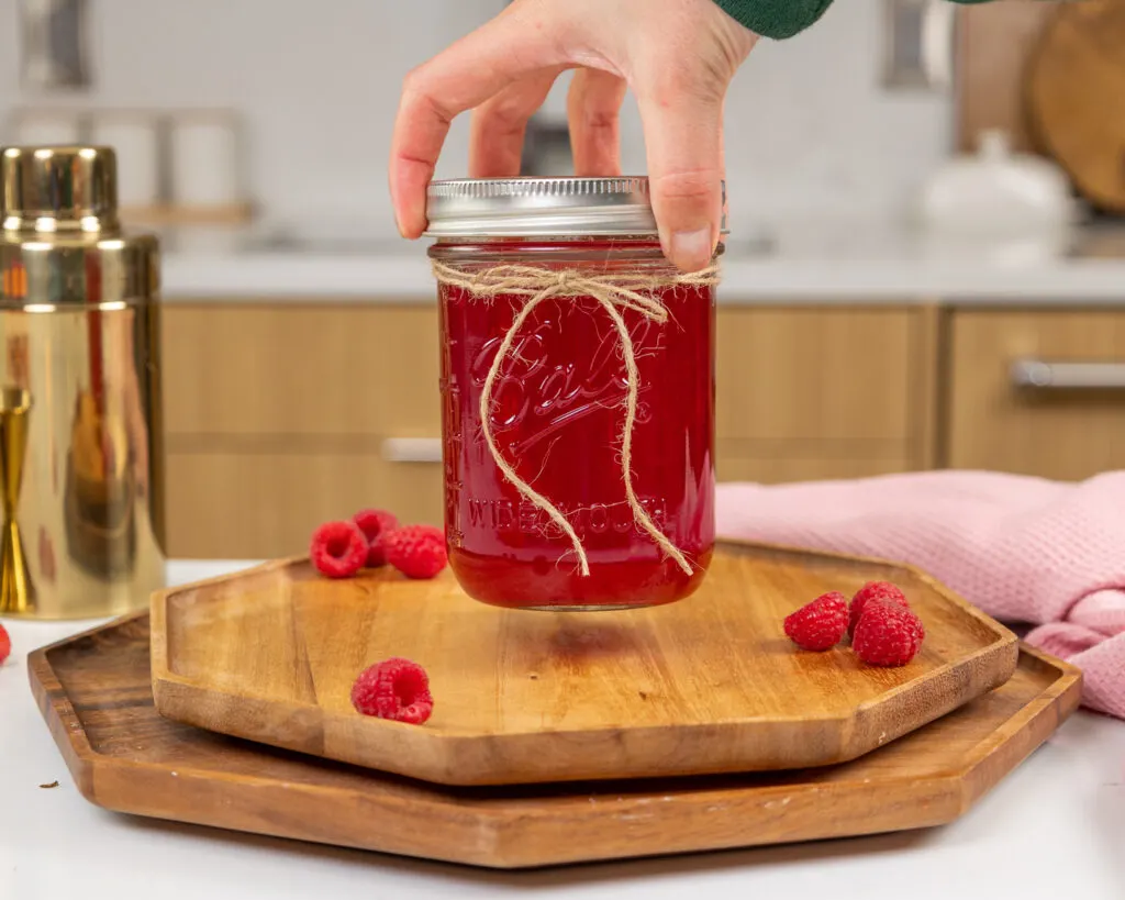 image of raspberry simple syrup being stored in a mason jar