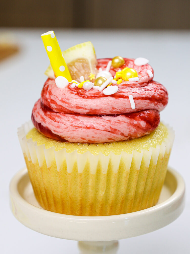 image of a raspberry lemonade cupcake decorated with cute sprinkles and lemon slices