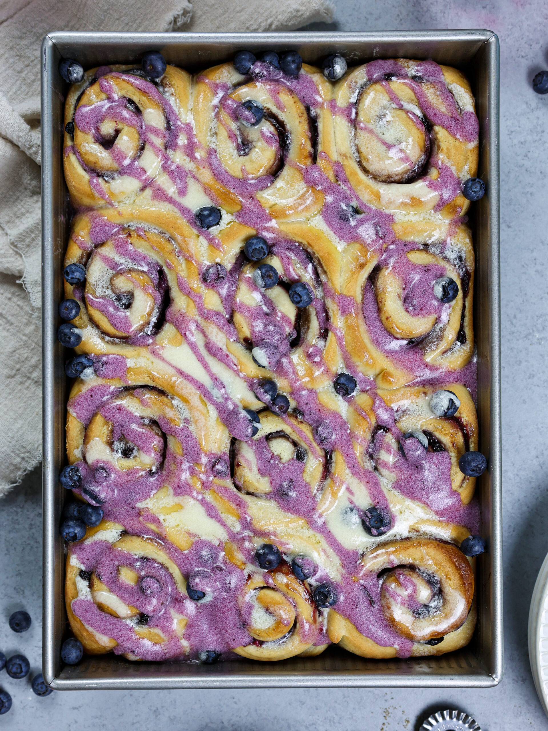 image of blueberry cinnamon rolls that have been baked and drizzled with vanilla and blueberry glaze