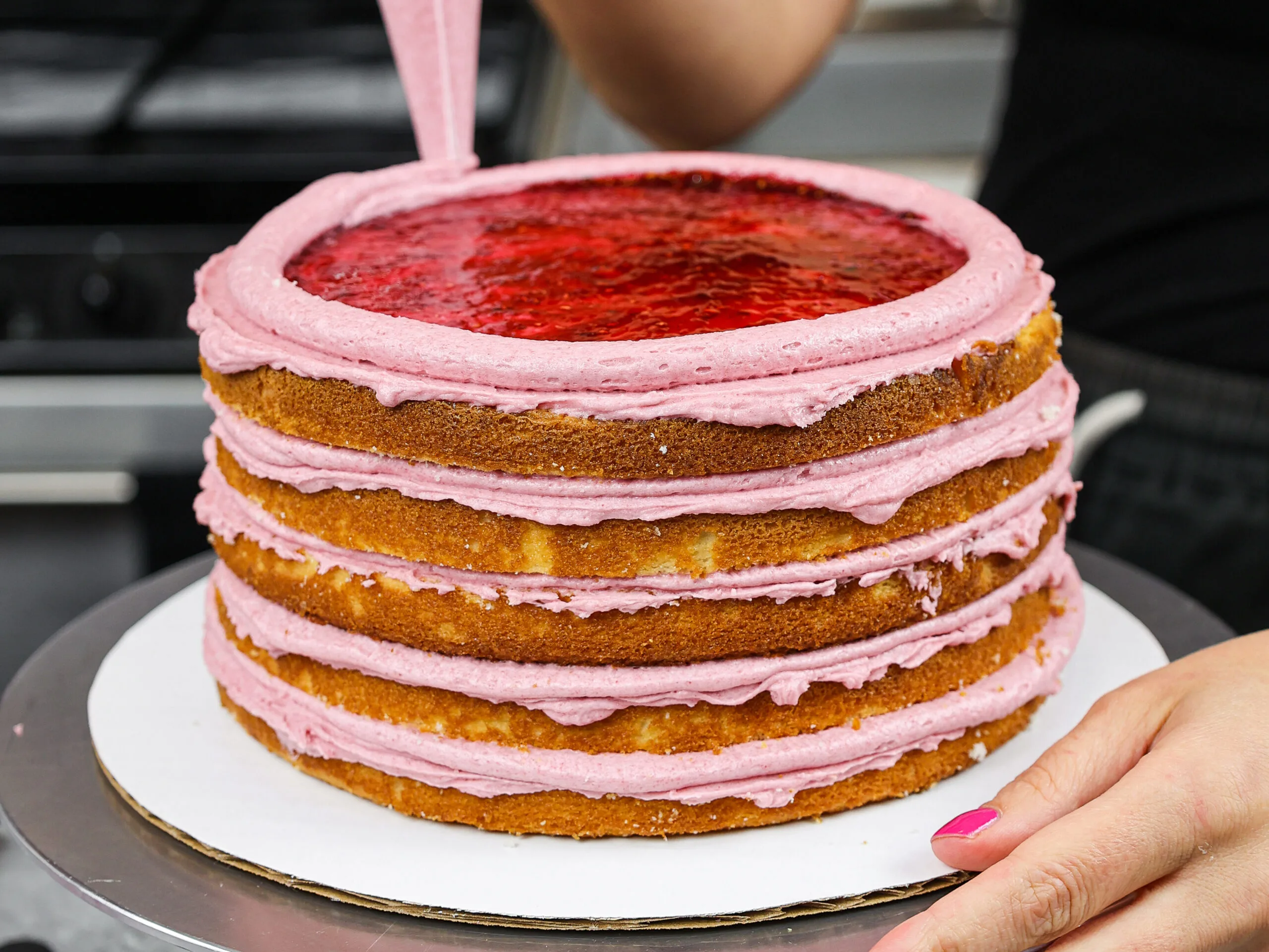 image of a cake being filled with raspberry jam surrounded by a frosting ring