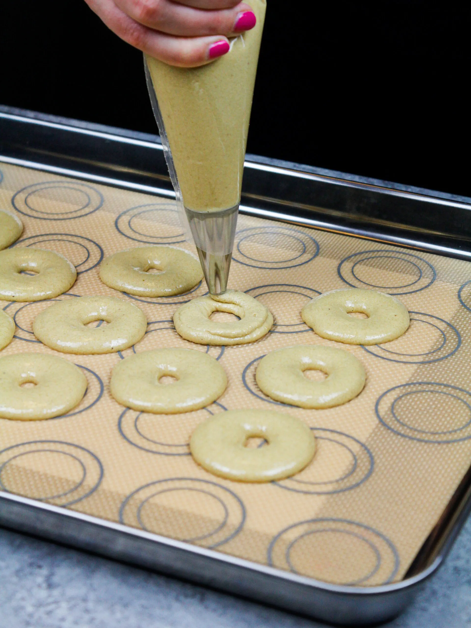 image of macaron batter being piped into rings to make donut shaped macarons