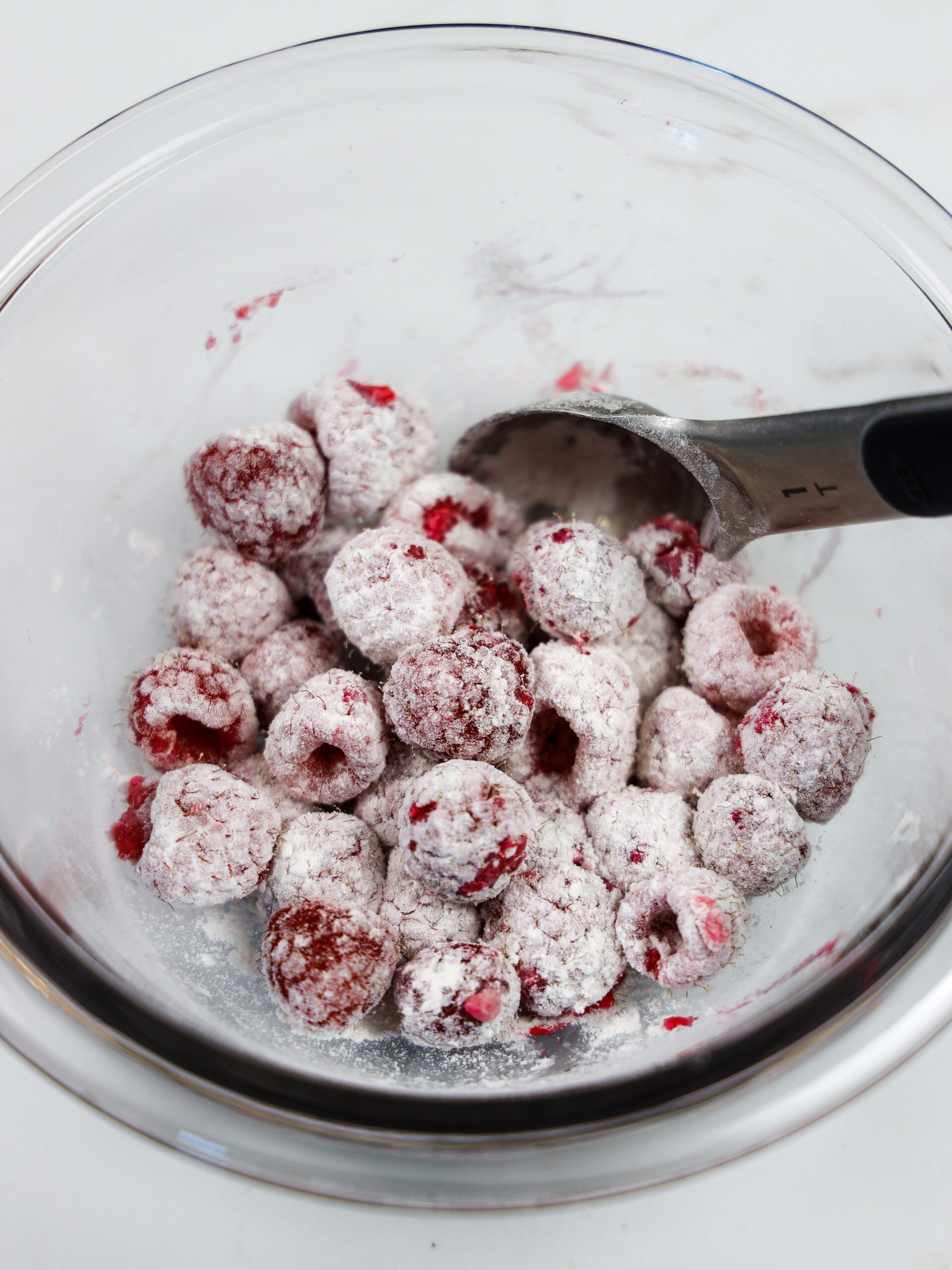 image of raspberries tossed in flour to prevent them from sinking as these raspberry cupcakes bake