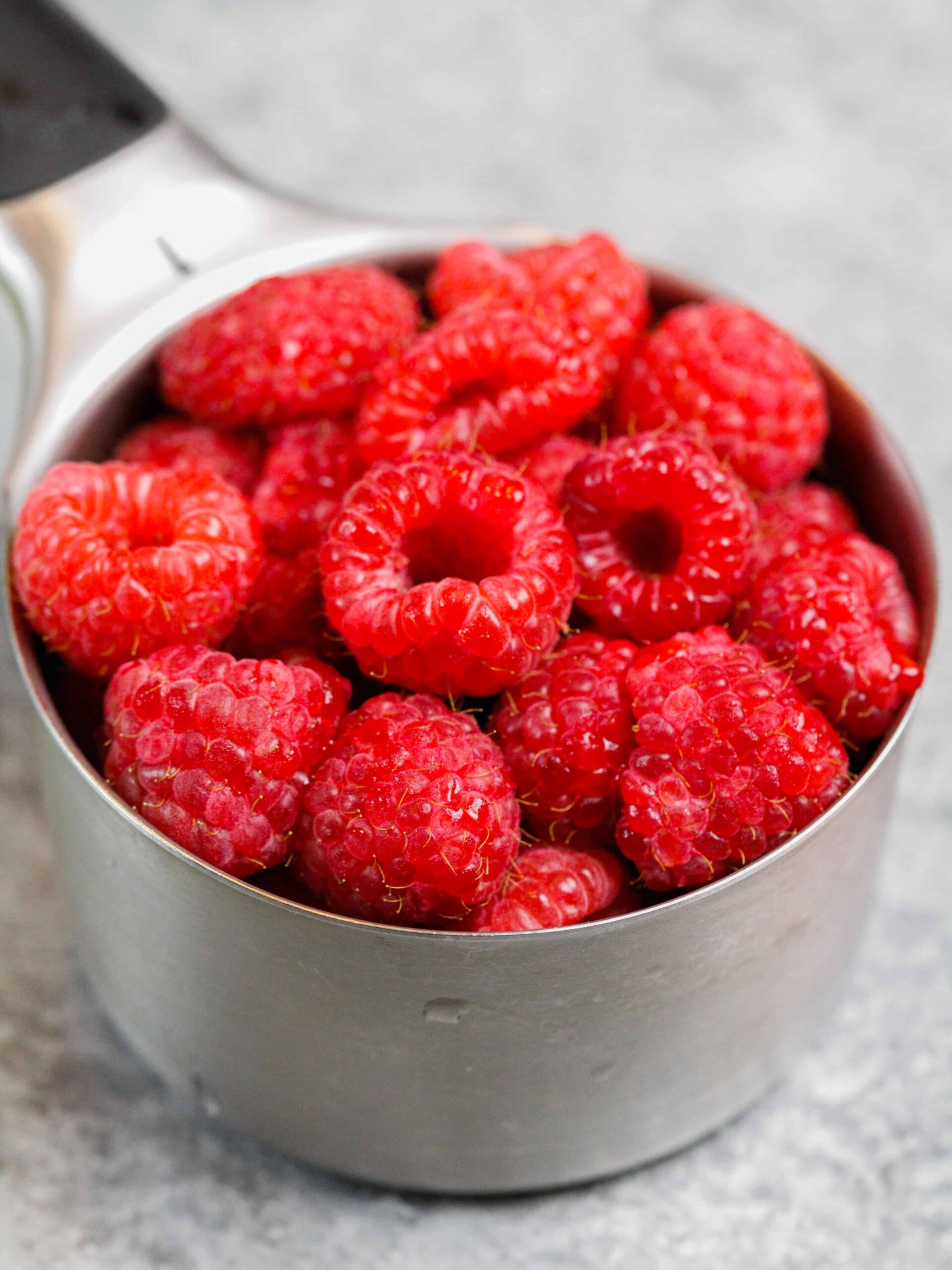 image of fresh raspberries in a measuring cup ready to be made into a raspberry swirled cheesecake bar