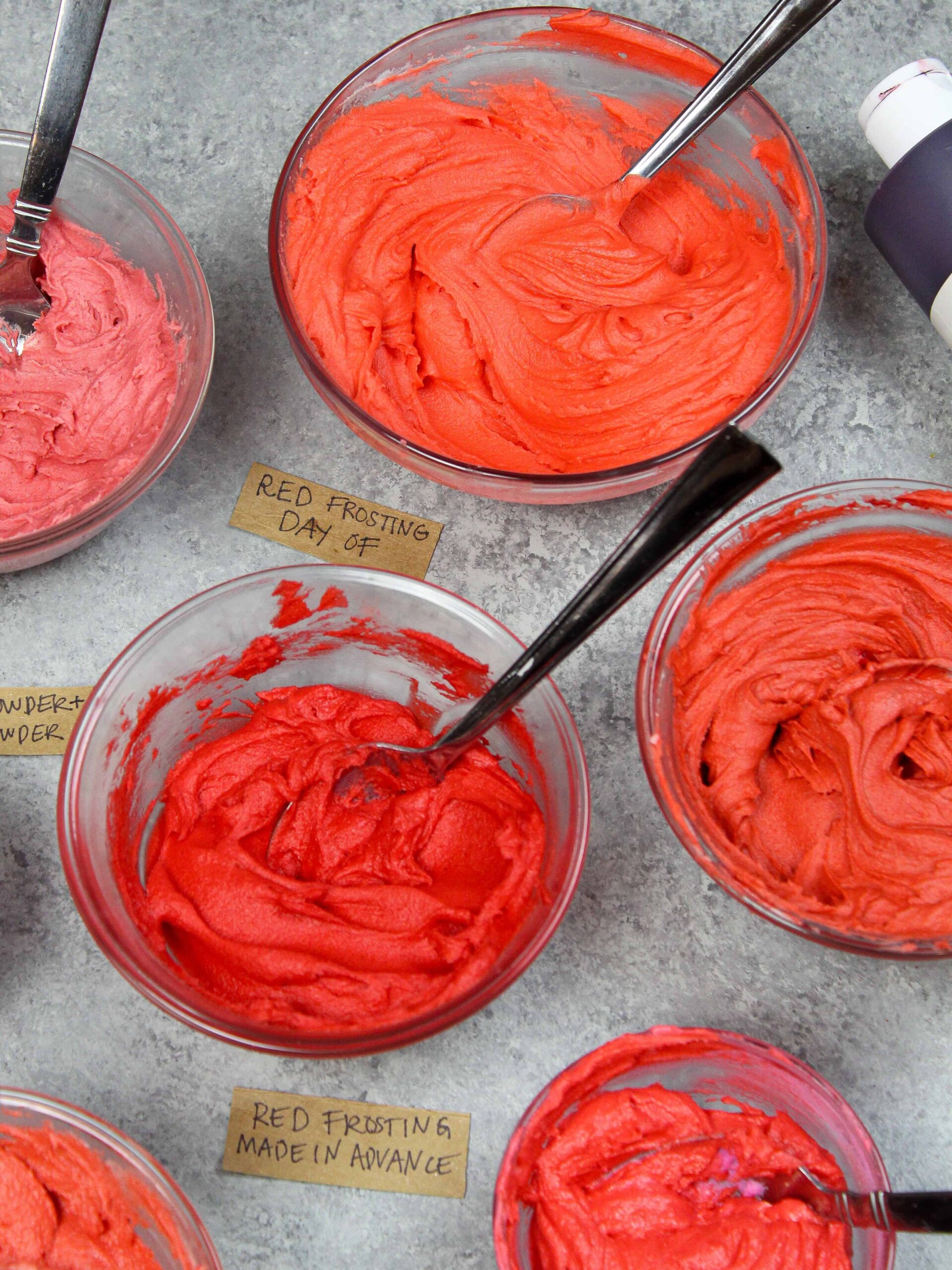 photo comparing red frosting made ahead of time against frosting made the day of, showing that the frosting made in advance is a much deeper and brighter shade of red