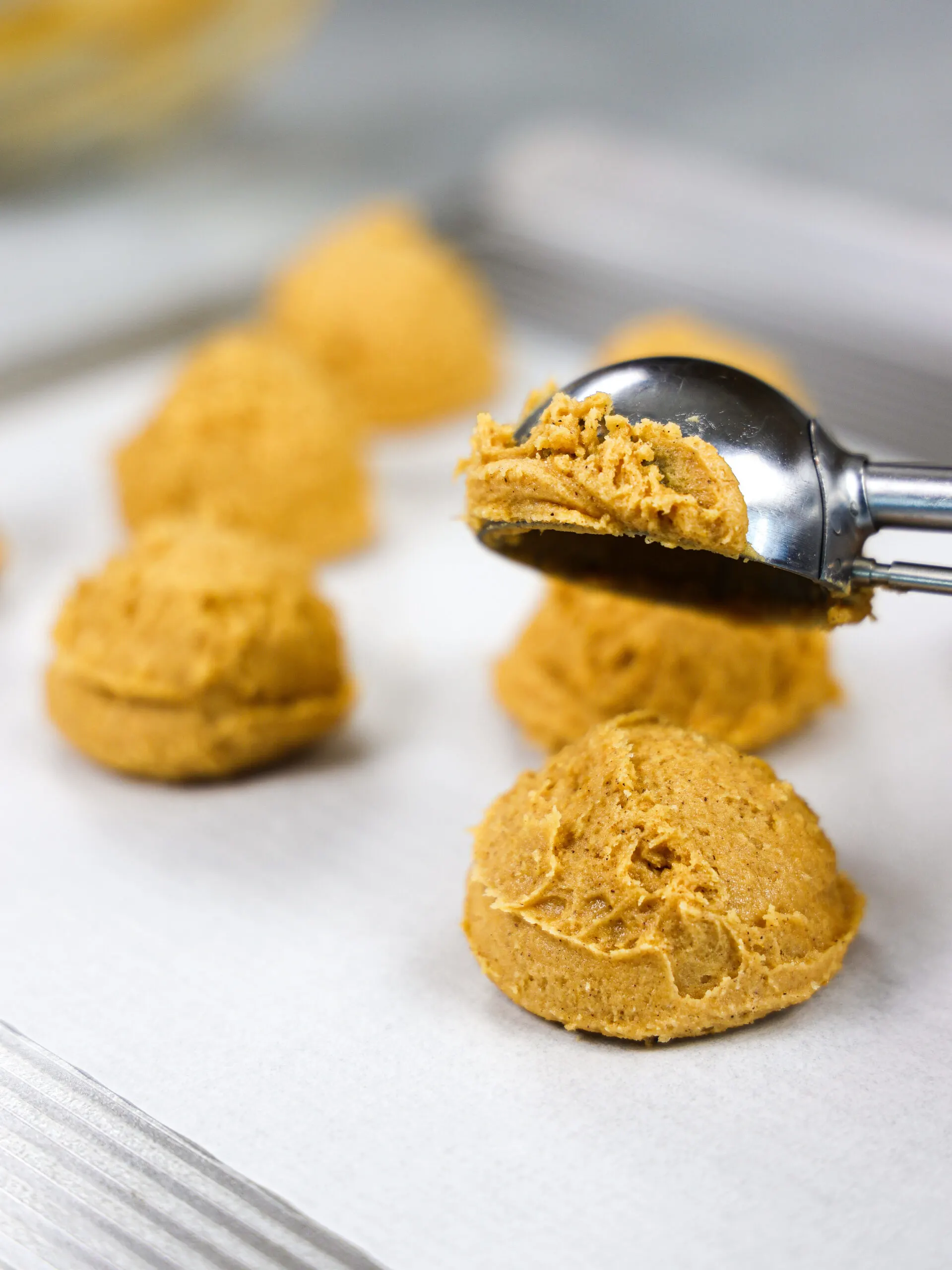 image of pumpkin cookie dough being scooped on to a baking mat to chill